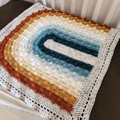 a crocheted blanket on top of a bed next to a radiator