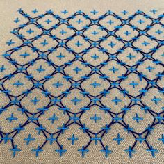 the blue thread is stitched on top of white fabric with small crosses in it