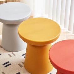 three different colored stools sitting on the floor