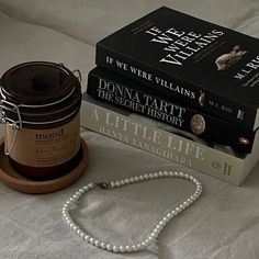 two books and a necklace on a bed