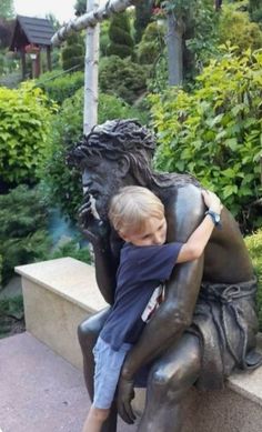 a young boy hugging a bronze statue in front of some bushes and trees with the caption, la tetura es un regolo de dio de dios