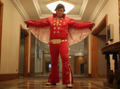 a man dressed in red and gold is walking down the hall with his hands on his hips