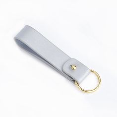 a silver key chain with a gold ring on the end and a white strap around it