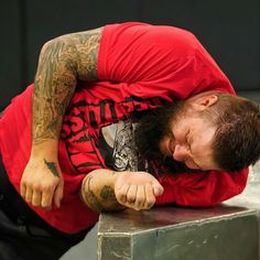 a man with tattoos on his arms and chest is leaning over a metal table while looking down