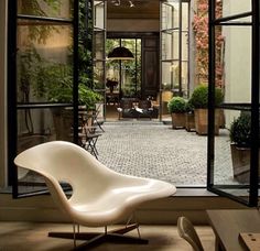 a white chair sitting in front of an open window next to a brick flooring area