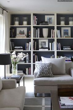 a living room filled with lots of books and vases on top of a table