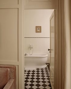 a bathroom with a checkered floor and bathtub next to a doorway that leads into another room