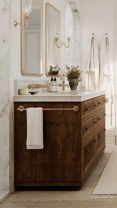 a bathroom with marble counter tops and wooden cabinets, along with white towels hanging on the wall