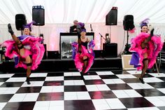 two women in pink and purple dresses dancing on a black and white checkered floor