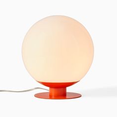 an orange table lamp sitting on top of a white surface next to a light bulb