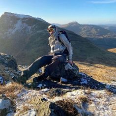 a man sitting on top of a rock in the mountains