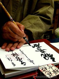 a man is writing chinese characters on paper