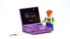 a lego man next to a purple electronic device with keychain on the side
