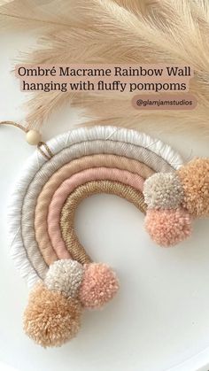 the macrame rainbow wall hanging with fluffy pompoms is shown on a white plate
