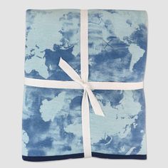 a blue and white tie dye blanket wrapped in a white ribbon with a world map on it