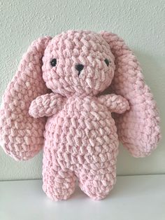 a pink crocheted stuffed animal sitting on top of a white table next to a wall