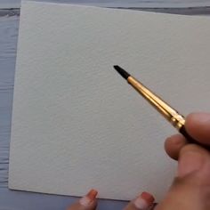a person holding a pen in their left hand and writing on a piece of paper