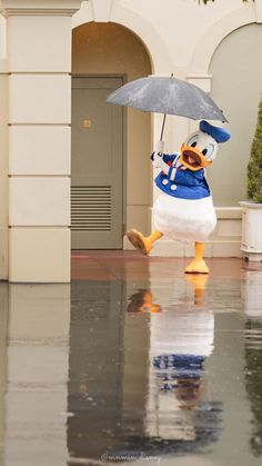 a ducky holding an umbrella in the rain