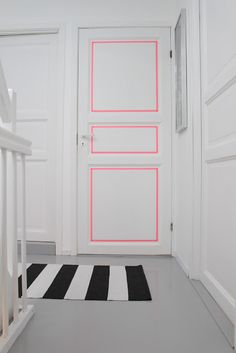 a white door with pink lines painted on it and a black and white striped rug