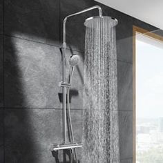 an open shower head with the rain running down it's side and windows in the background