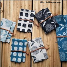 four small notebooks tied together on a wooden table with blue and white designs,