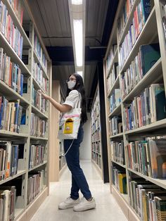 a woman wearing a face mask in a library with bookshelves full of books