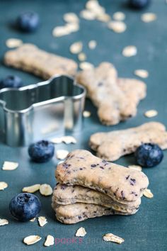 blueberries and cookies are on the table next to a cookie tin with dog biscuits