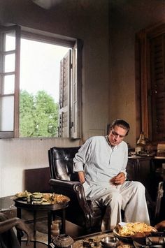 a man sitting in a chair with food on the table