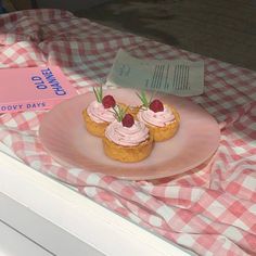 a pink plate topped with cupcakes on top of a checkered table cloth