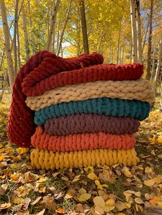 a pile of knitted blankets sitting on top of leaves