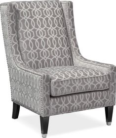 a gray and white chair with an intricate pattern on the armrest, in front of a