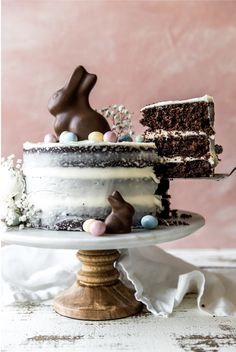 a chocolate cake with white frosting and candies on top is sitting on a pedestal