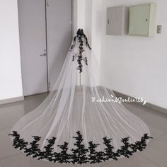 a wedding veil with black flowers on the bottom and white lace at the bottom, hanging from a wall