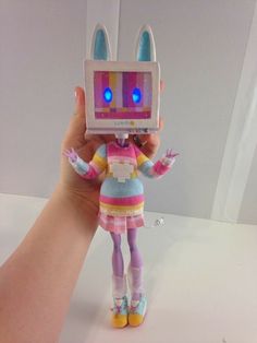 a hand holding up a toy with an electronic device in it's head and ears