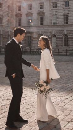 a man and woman standing next to each other holding hands