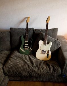 two guitars sitting on top of a couch