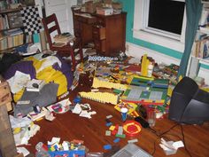 a messy living room filled with toys and clutter on the floor next to a laptop computer