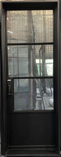 a black door is open on the side of a building with glass panels and metal railings