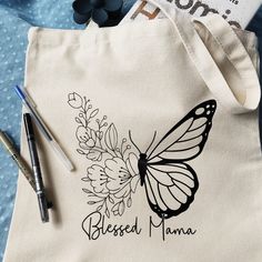 a white tote bag with a butterfly on it and the words blessed mama written in black ink