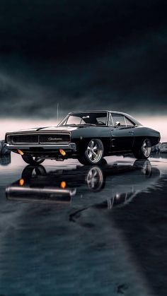 an old muscle car is parked on the water in front of a dark sky with clouds