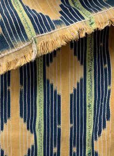 an up close view of a blue and yellow striped fabric with fringes on it