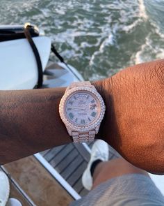 a close up of a person wearing a watch on their wrist with the ocean in the background