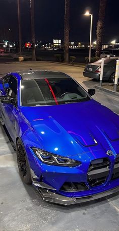 a blue sports car parked in a parking lot next to some palm trees at night