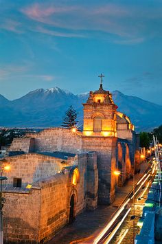 an old church lit up at night with mountains in the backgrouund and lights on