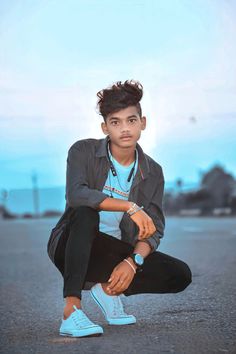 a young man sitting on the ground wearing blue sneakers