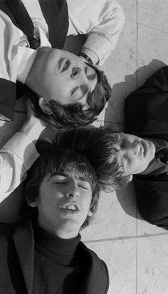 three young men laying on the ground with their heads together, looking up at the camera