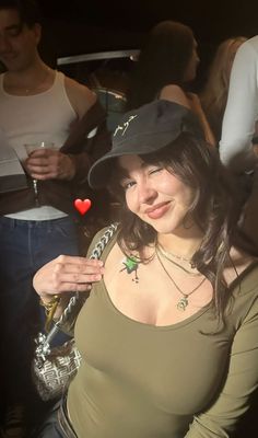 a woman wearing a hat poses for the camera with other people in the background at a party