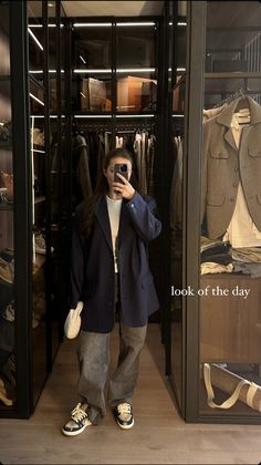 a woman taking a selfie in front of a closet full of jackets and pants