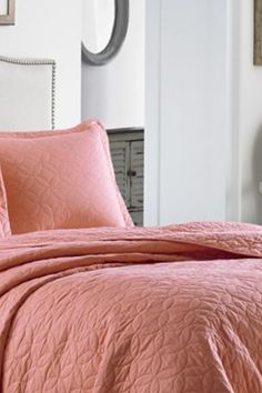 a bed with a pink comforter and pillows