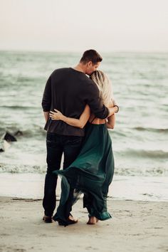 a man and woman embracing on the beach